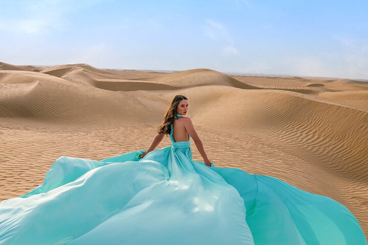 Experience the magic of Dubai's desert landscape while wearing a stunning flying dress transforming your photoshoot into a unique adventure among the golden dunes and endless sky.